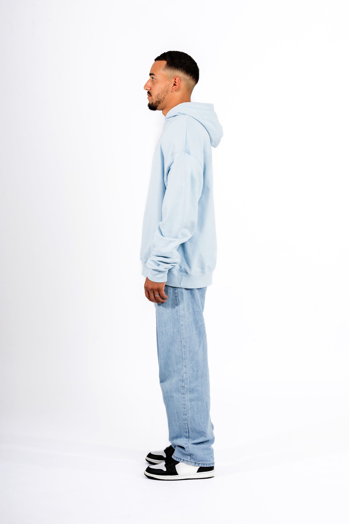 Seitenansicht eines Mannes, der einen hellblauen Harry-Potter-Hoodie trägt, vor einem neutralen weißen Hintergrund.