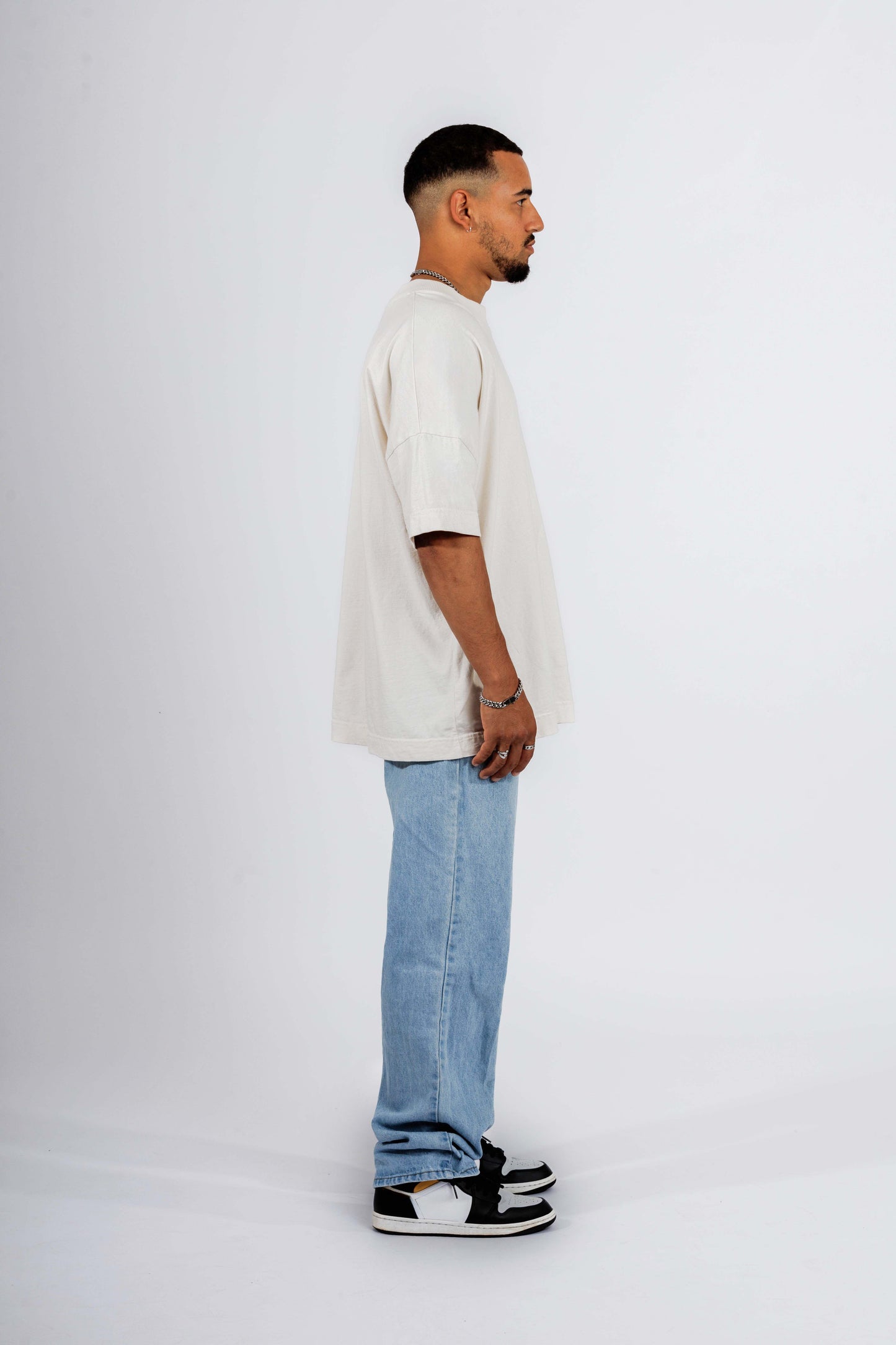 Seitenansicht eines Mannes, der ein weißes Harry-Potter-T-Shirt mit Gryffindor-Löwe-Design trägt, vor neutralem weißen Hintergrund.